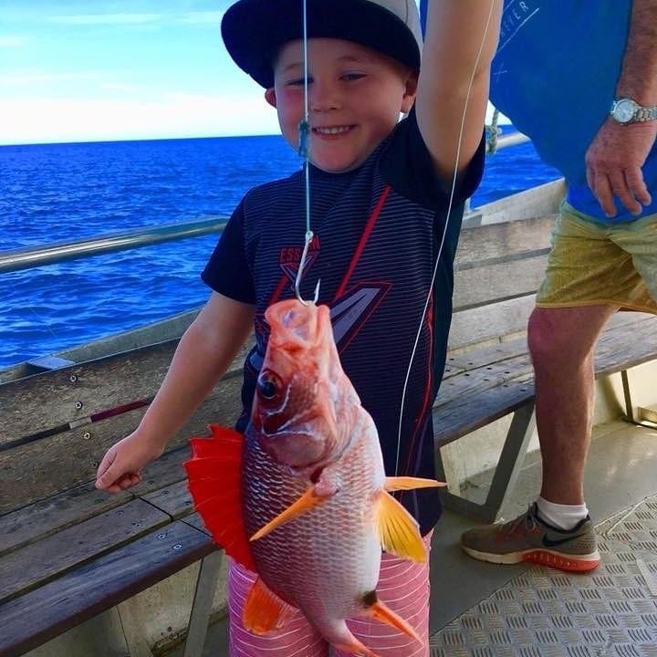 A children smiles while holding a capture fish