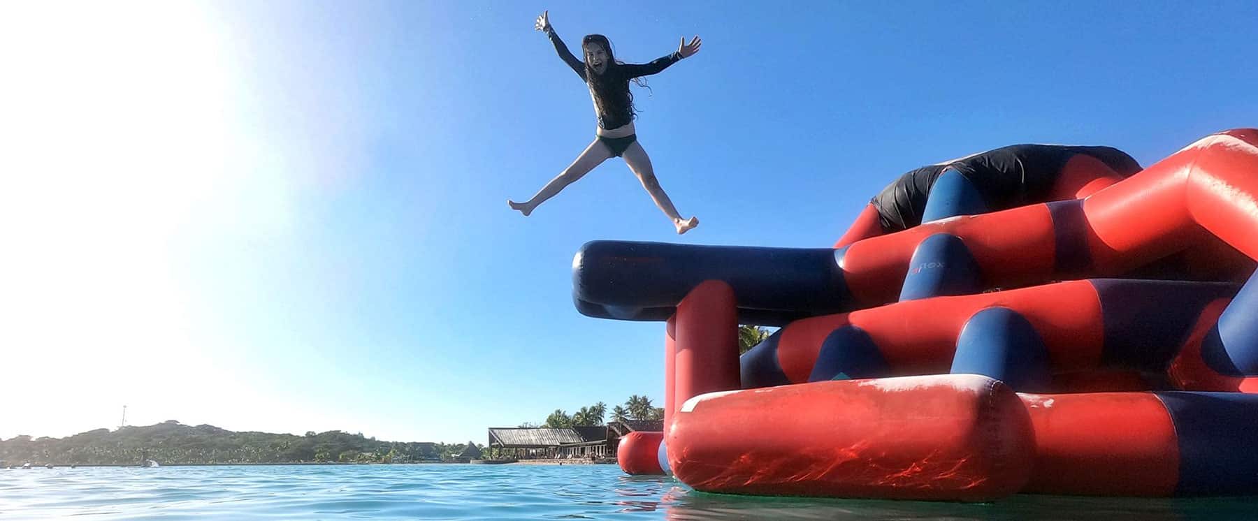A young woman jumping from the slide, A water and mountain background