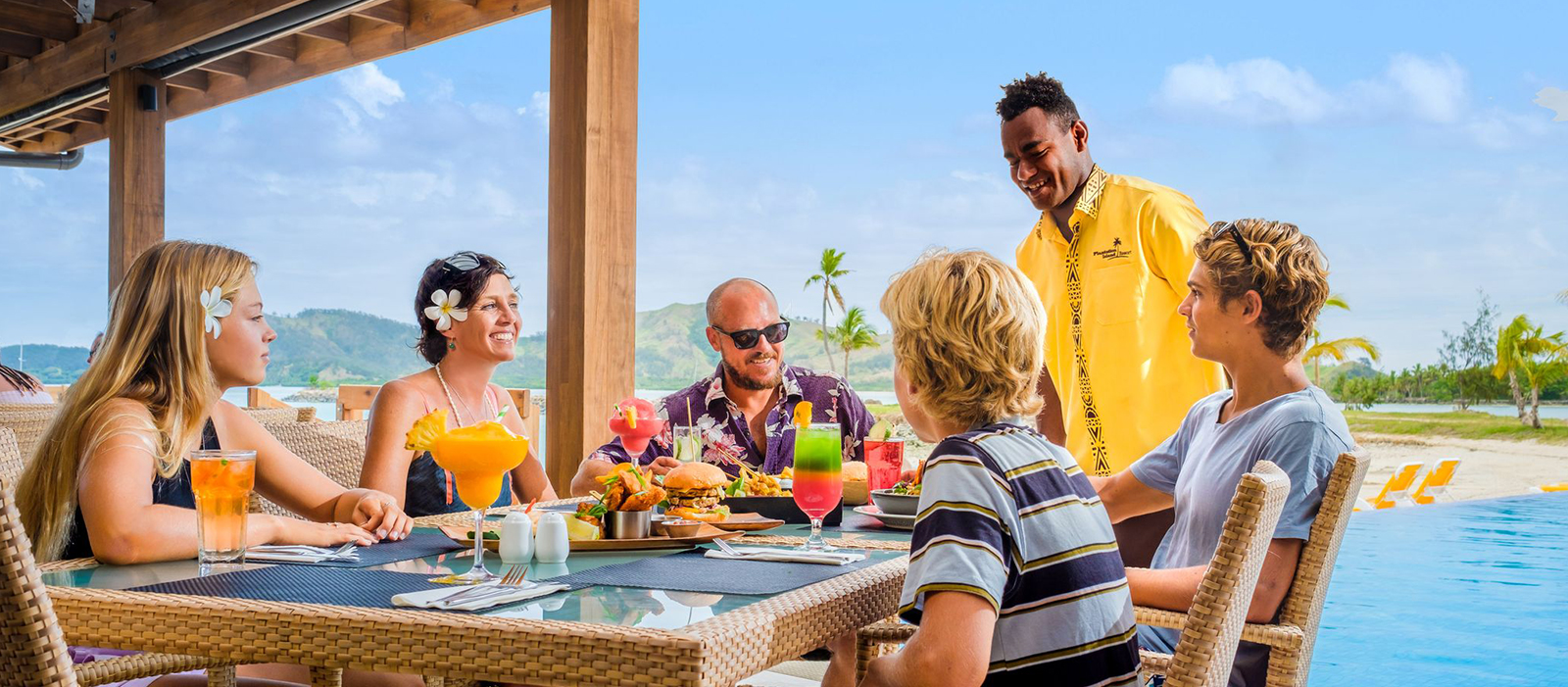 A group of people talking and smiling in front of the crew with sea mountain background