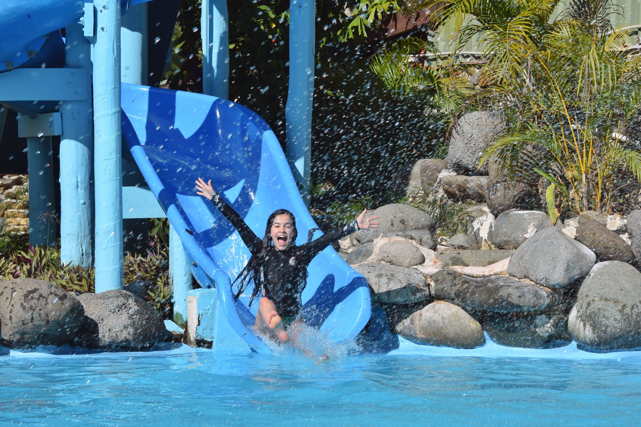 A woman happily slides to the pool.