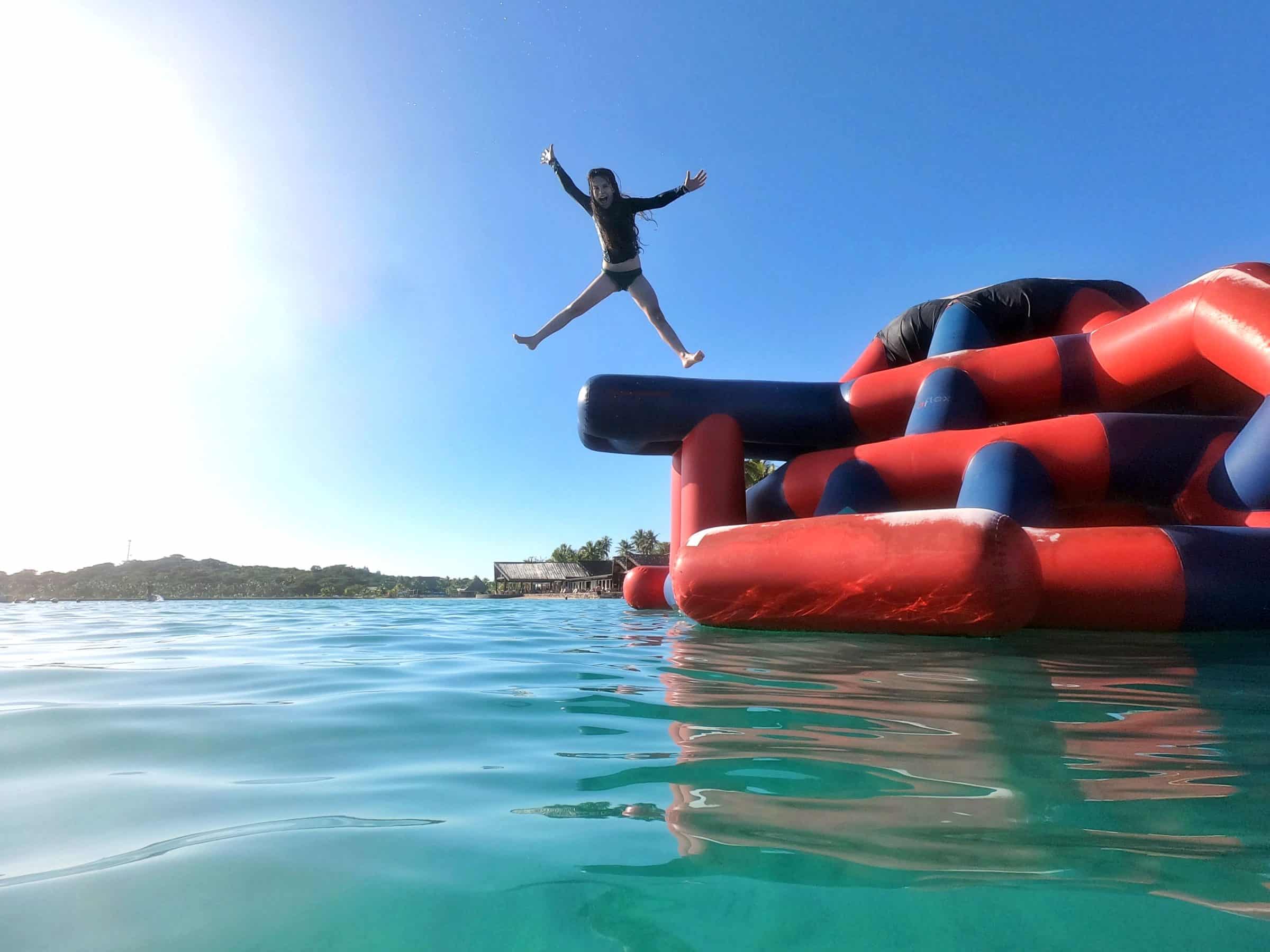 A young woman jumping from the slide, A water and mountain background