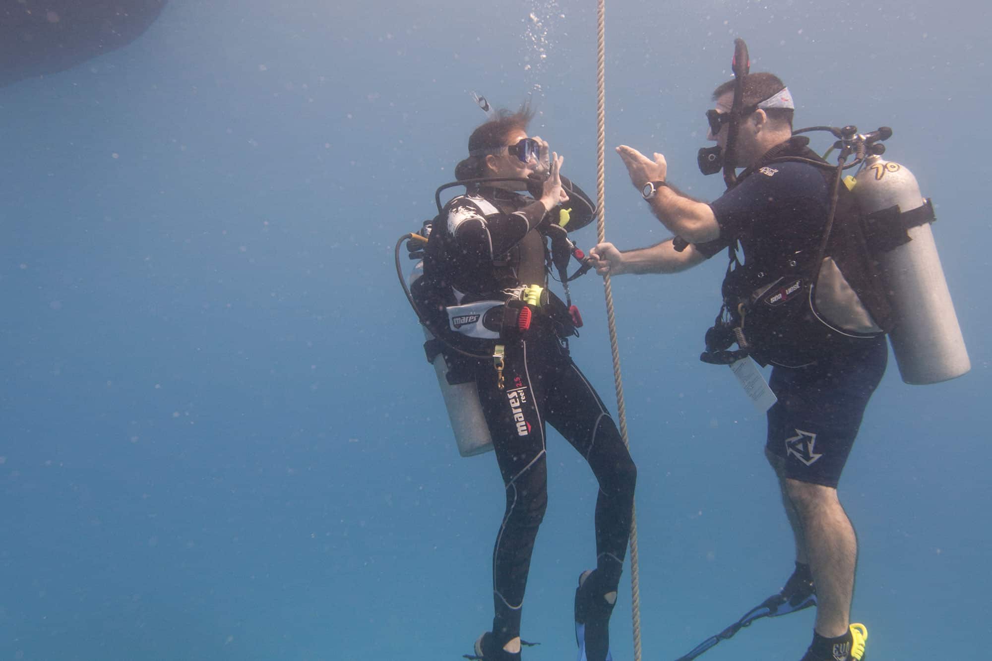 Two divers wearing rebreather and holding rope