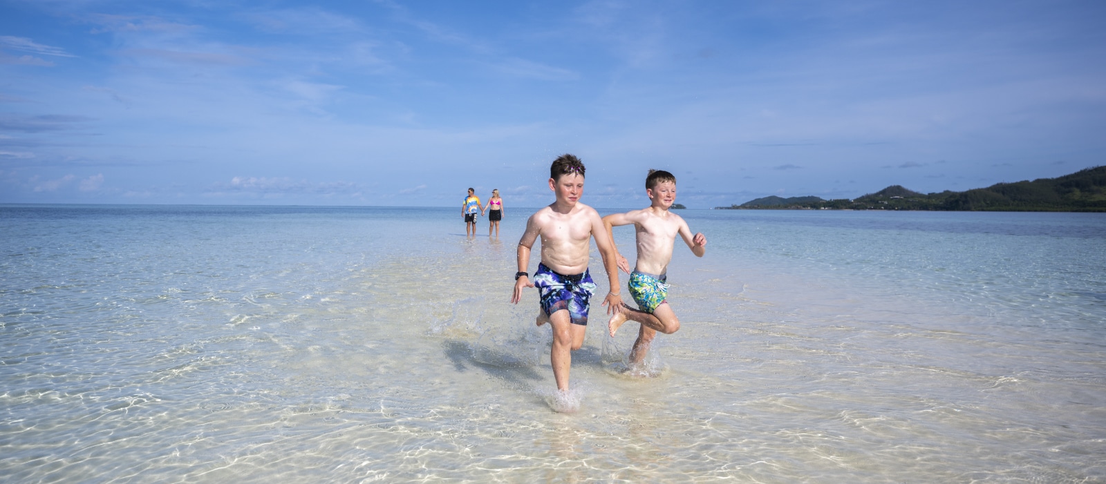 A young kids running in the sea with man and woman background