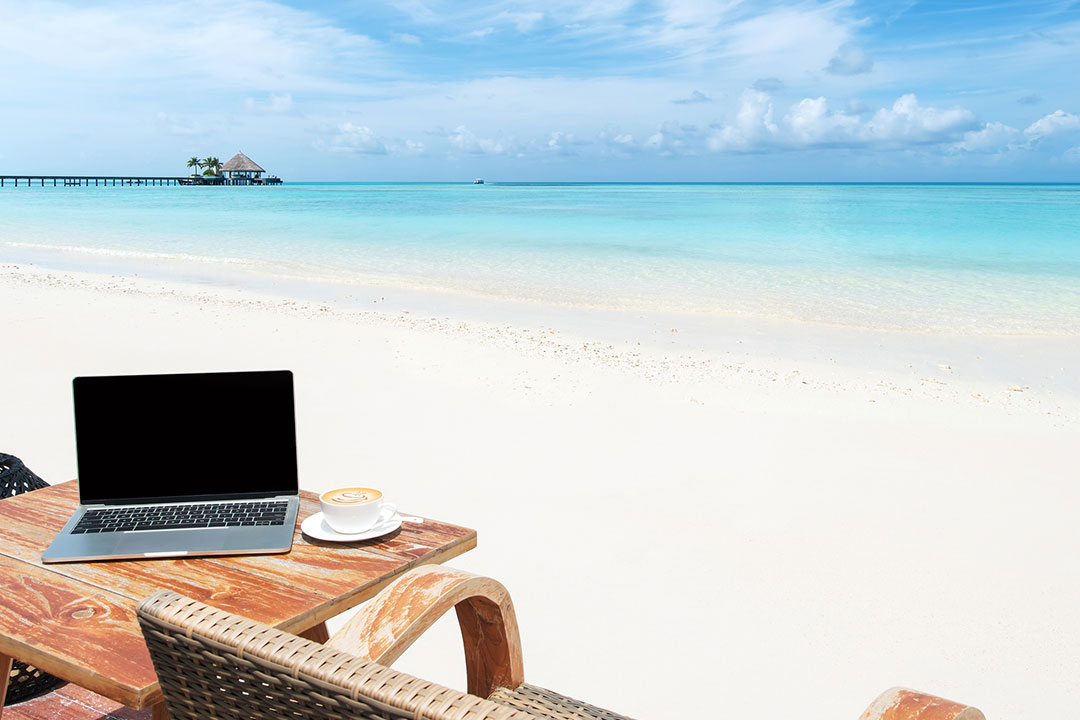 A beautiful view of the sea from the seashore with laptop on the table.